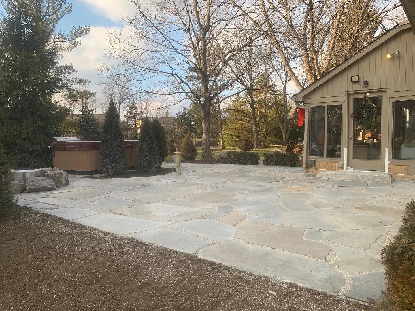 Natural flagstone patio with a stone fire pit and hot tub