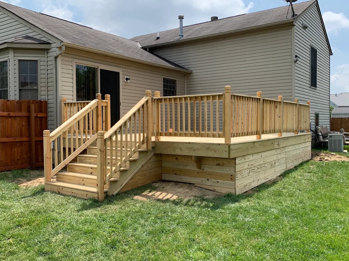 Custom backyard deck with railing and stairs by KVI Construction