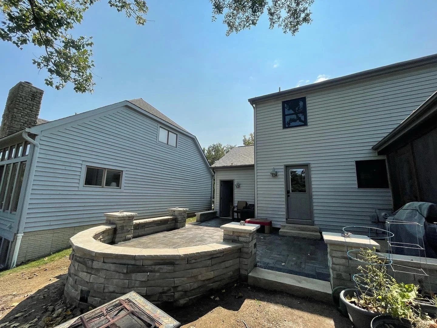 Paver patio with a curved stone seat wall and pillars