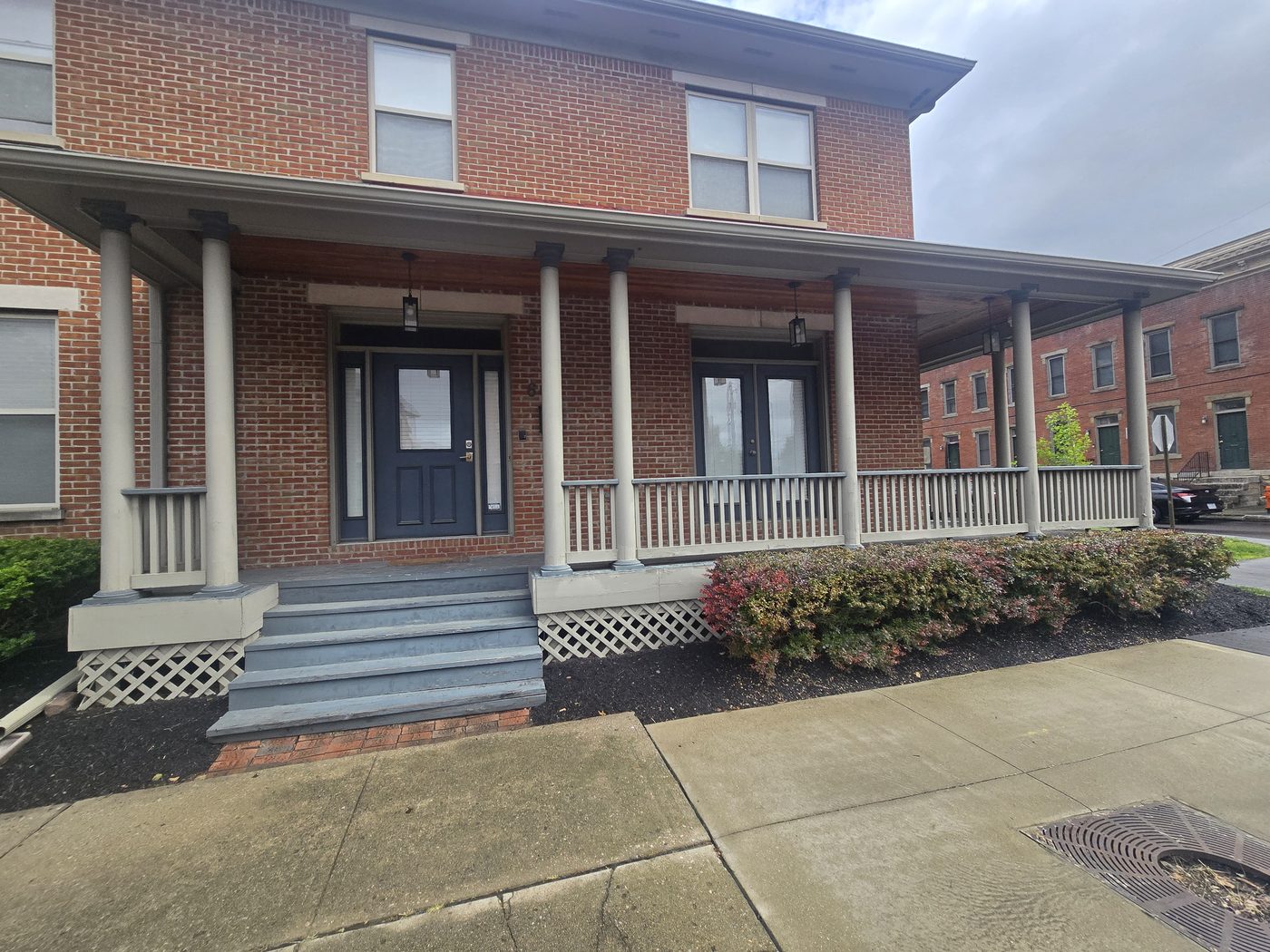 Front of a historic brick home in Italian Village with a wrap around porch before repairs