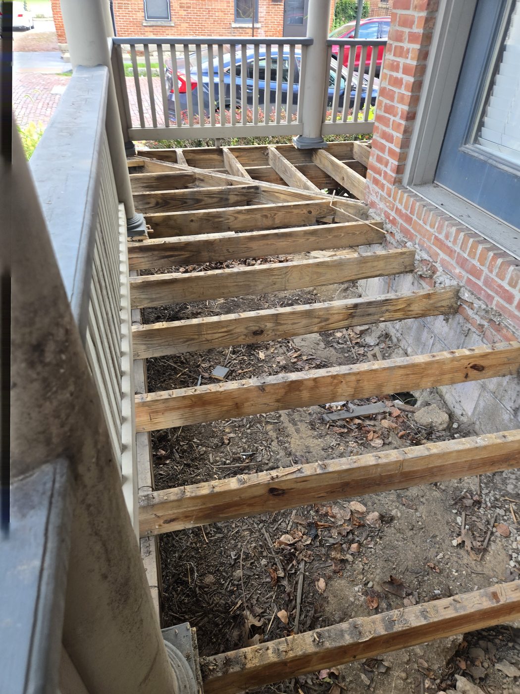 Porch deck boards removed, exposing the old joists and framing